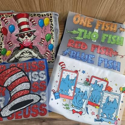 Three Dr. Seuss themed tees on a wood table.