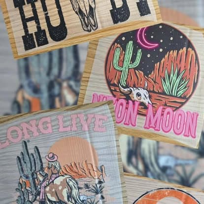 A spread of western themed heat transfer prints laid out on a wood workbench.