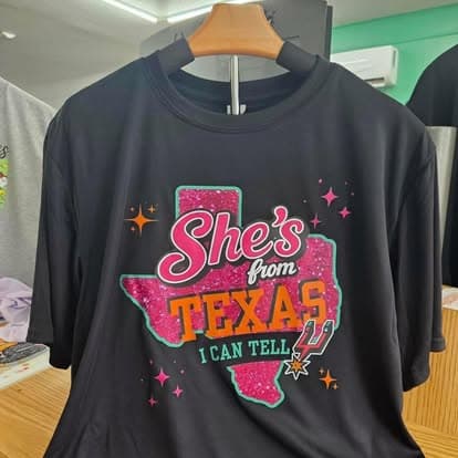 A tee reading She's From Texas, I Can Tell.